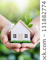 Tiny wooden house in hands with sprout, eco friendly home concept. 131882774