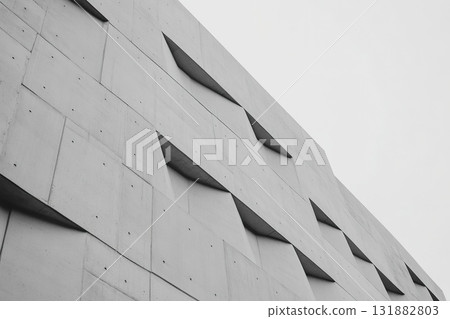 Modern Concrete Building Facade with Geometric Indentations Against a Gray Sky. Modern Concrete Building Facade with Geometric Indentations Against a Gray Sky. 131882803
