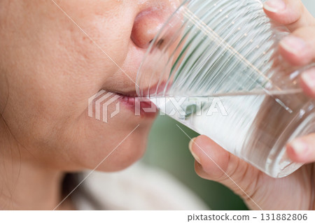 Hydration and Wellness. A close-up of an elderly woman taking a refreshing sip of water. Hydration and Wellness. A close-up of an elderly woman taking a refreshing sip of water. 131882806