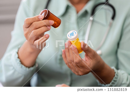 Medication Management and Compassionate Healthcare. The elderly doctor examines medication containers during a patient consultation. Medication Management and Compassionate Healthcare. The elderly doctor examines medication containers during a patient consultation. 131882819
