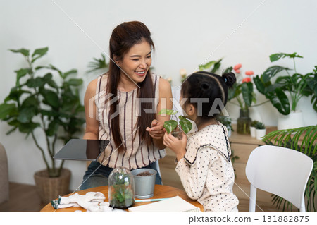 Hands-on Gardening and Learning. A mother shares knowledge of plant care with her daughter, fostering sustainable practices. Hands-on Gardening and Learning. A mother shares knowledge of plant care with her daughter, fostering sustainable practices. 131882875