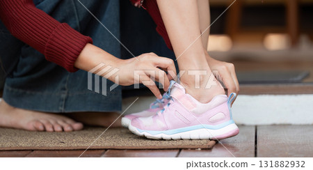 Putting on Shoes for School. A mother helps her daughter wear her sneakers before heading out. Putting on Shoes for School. A mother helps her daughter wear her sneakers before heading out. 131882932
