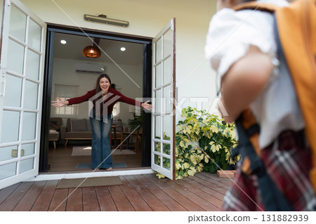 Return to School and Family Bonding. A mother welcoming her child home from school with open arms. Return to School and Family Bonding. A mother welcoming her child home from school with open arms. 131882939