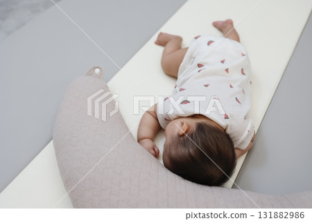 Full-body image of a Japanese baby sleeping face down next to a nursing cushion Full-body image of a Japanese baby sleeping face down next to a nursing cushion 131882986