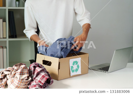 Clothing Recycling and Sustainability. A person sorting through clothes, preparing to donate them for recycling in an eco-conscious effort. 131883006