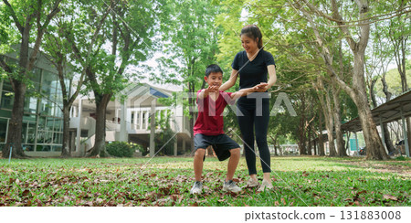 Strength Training and Family Fun. A woman assists a boy in developing strength with a bonding exercise. 131883008