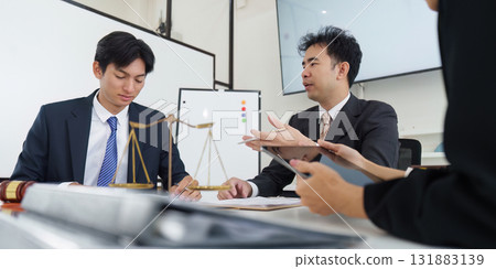 Legal Analysis and Client Interaction. A lawyer discussing legal matters with a client at a conference table. 131883139