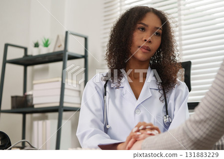 Patient Consultation and Listening. A doctor attentively listens to her patient during a consultation, fostering a supportive environment. 131883229