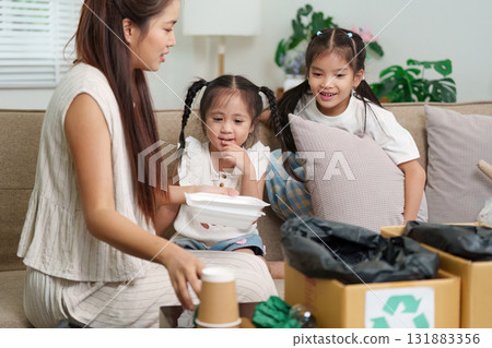 Sustainability and Family Engagement. A mother teaches her children about recycling through hands-on activities at home. 131883356
