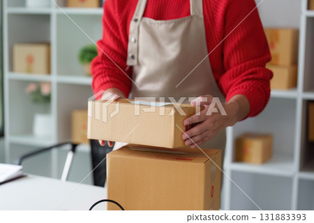 Entrepreneur and Packaging. An entrepreneur prepares a package for shipment while showcasing online selling. Entrepreneur and Packaging. An entrepreneur prepares a package for shipment while showcasing online selling. 131883393