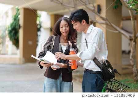Sustainability and Collaboration. Two students discussing environmental initiatives while reviewing notes outdoors. 131883409