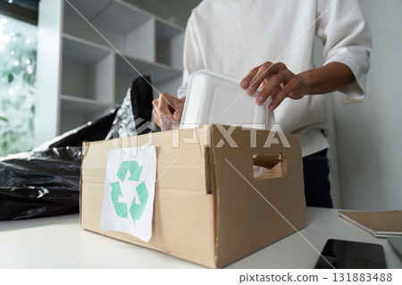 Food Container Recycling and Sustainability. An individual organizing foam containers for recycling, championing eco-friendly practices. 131883488