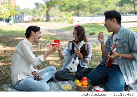 Friends enjoying a picnic in the park with drinks and a ukulele Friends enjoying a picnic in the park with drinks and a ukulele 131883496