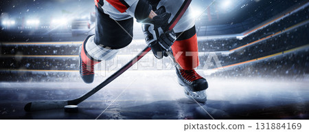 A close-up of a hockey player on a skating rink. Skates, stick, and puck close-up on the ice. A hockey player prepares to shoot the puck on an ice 131884169