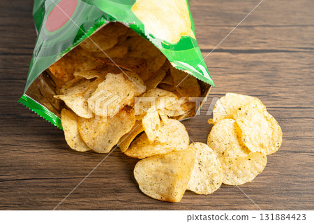Potato chips, delicious spicy for crips, thin slice deep fried snack fast food in open bag. Potato chips, delicious spicy for crips, thin slice deep fried snack fast food in open bag. 131884423