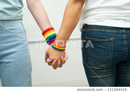 Asian LGBT couple woman holding hand wearing rainbow wristband. Asian LGBT couple woman holding hand wearing rainbow wristband. 131884426