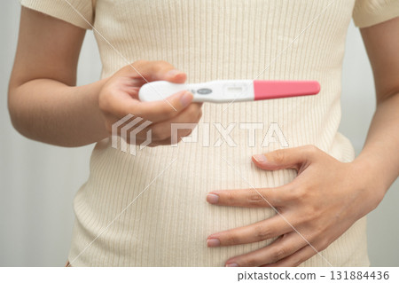 Asian holding pregnancy test for female of ovulation day, fetus, maternity, childbirth, birth control. Asian holding pregnancy test for female of ovulation day, fetus, maternity, childbirth, birth control. 131884436