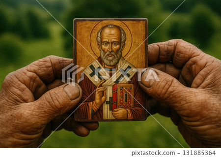 Weathered hands holding a painted religious icon of a bearded saint with a golden halo, set against a lush green natural background, AI Generative 131885364