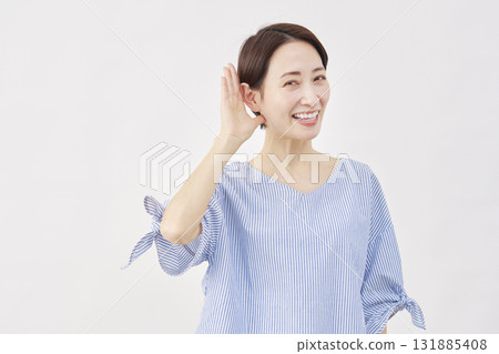 Woman, middle-aged, gesture of listening with hand on ear, white background, looking at camera Woman, middle-aged, gesture of listening with hand on ear, white background, looking at camera 131885408