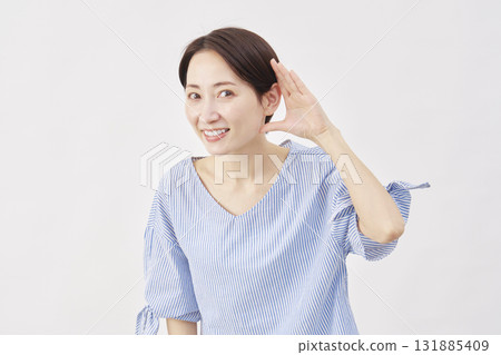 Woman, middle-aged, gesture of listening with hand on ear, white background, looking at camera 131885409