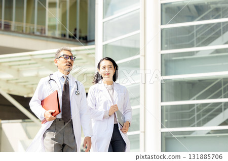 Men and women wearing white coats walking Men and women wearing white coats walking 131885706