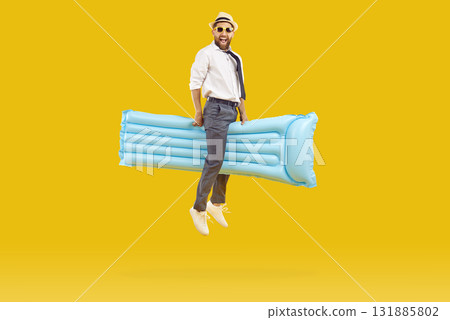 Funny man in office clothes, hat and sunglasses riding on water mattress and flying in air 131885802
