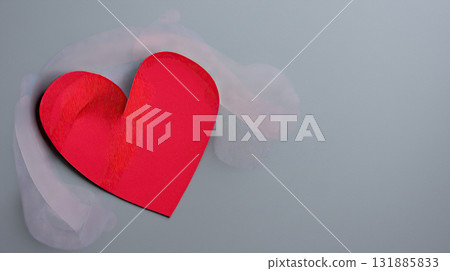 Red paper heart on gray background with soft translucent cloth adding romantic mood and textured detail, minimal composition evoking love and tenderness Red paper heart on gray background with soft translucent cloth adding romantic mood and textured detail, minimal composition evoking love and tenderness 131885833