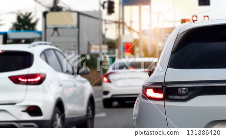 Rear side of luxury white car with trun on brake light. Traffic jam in the city. Environment in the city at evening time. Stop on the road by traffic red control. Rear side of luxury white car with trun on brake light. Traffic jam in the city. Environment in the city at evening time. Stop on the road by traffic red control. 131886420