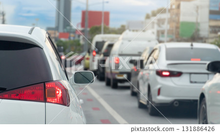Rear side of white luxury car with turn on brake light. Traffic jam on the road. Many car queue up in traffic jams in the city at day time. 131886426