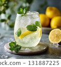 Refreshing lemonade with ice, lemon slice and fresh mint leaves in chilled glass on marble coaster, bright citrus beverage with condensation and natural summer vibe 131887225