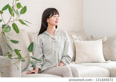 Smiling young Asian woman relaxing in the living room at home 131889872