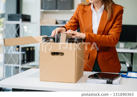 Happy and excited young beautiful Asian woman office worker celebrating her resignation, carrying her personal stuff. 131890363