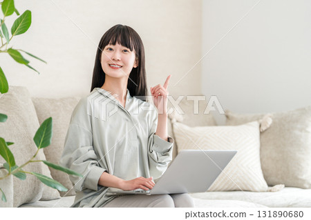 A woman using a computer on the sofa in the living room (video, side job, SNS, work from home) 131890680