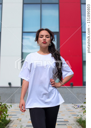 A young woman wearing a casual white tshirt enjoys her time outdoors in the park A young woman wearing a casual white tshirt enjoys her time outdoors in the park 131890803