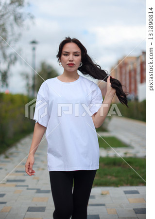 A Stylish Young Woman Dressed in an Oversized White TShirt and Comfortable Leggings 131890814