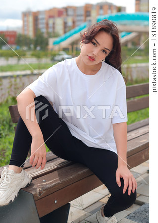 Chic Urban Portrait of a Young Woman Enjoying a Relaxing Moment Outdoors in the City Chic Urban Portrait of a Young Woman Enjoying a Relaxing Moment Outdoors in the City 131890819