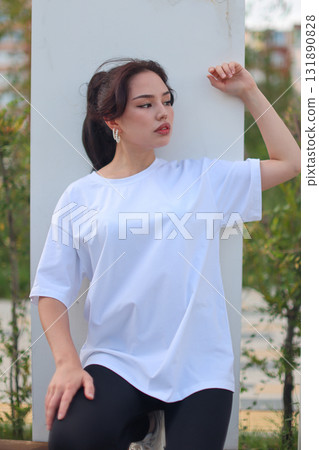 A Fashionable Young Woman is seen wearing a Casual White TShirt with style and flair A Fashionable Young Woman is seen wearing a Casual White TShirt with style and flair 131890828