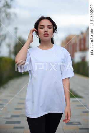 A Stylish Young Woman Dressed in an Oversized White TShirt and Comfortable Leggings A Stylish Young Woman Dressed in an Oversized White TShirt and Comfortable Leggings 131890844