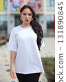 A young woman wearing a casual white tshirt enjoys her time outdoors in the park 131890845