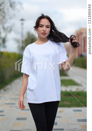 A Stylish Young Woman Dressed in an Oversized White TShirt and Comfortable Leggings A Stylish Young Woman Dressed in an Oversized White TShirt and Comfortable Leggings 131890848