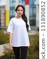 A young woman wearing a casual white tshirt enjoys her time outdoors in the park 131890852