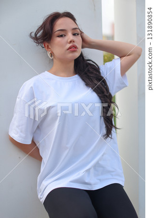 A Fashionable Young Woman is seen wearing a Casual White TShirt with style and flair A Fashionable Young Woman is seen wearing a Casual White TShirt with style and flair 131890854