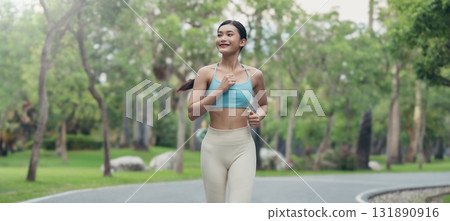 Young runner Asian woman jogging in park path, skinny fit in sports wear outfit leggings and top Young runner Asian woman jogging in park path, skinny fit in sports wear outfit leggings and top 131890916