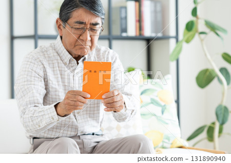 Senior man holding pension book in living room 131890940