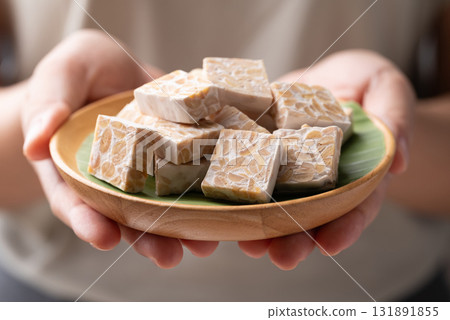 Tempeh made from fermented soybeans on wooden plate holding by hand, Traditional Indonesian food 131891855