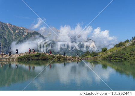 People walking against the backdrop of rising clouds at Happo Pond (Happo Ridge), Hakuba Village, Nagano Prefecture, September 131892444