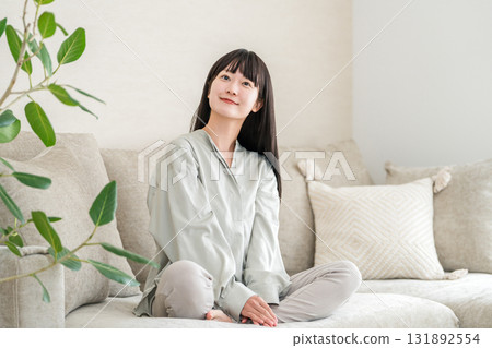 Smiling young Asian woman relaxing in the living room at home 131892554