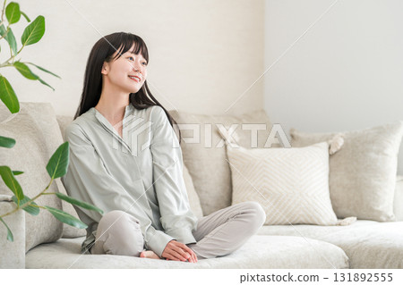 Smiling young Asian woman relaxing in the living room at home 131892555