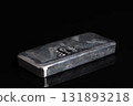 Silver bar on a glass plate, against black background. Stamped cast silver ingot, of one kilogram, about 32 troy oz of metal, with a purity of 999.0, that is 99.9 percent pure silver. Side view. Photo 131893218