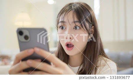 A young woman is surprised at her smartphone screen 131893677